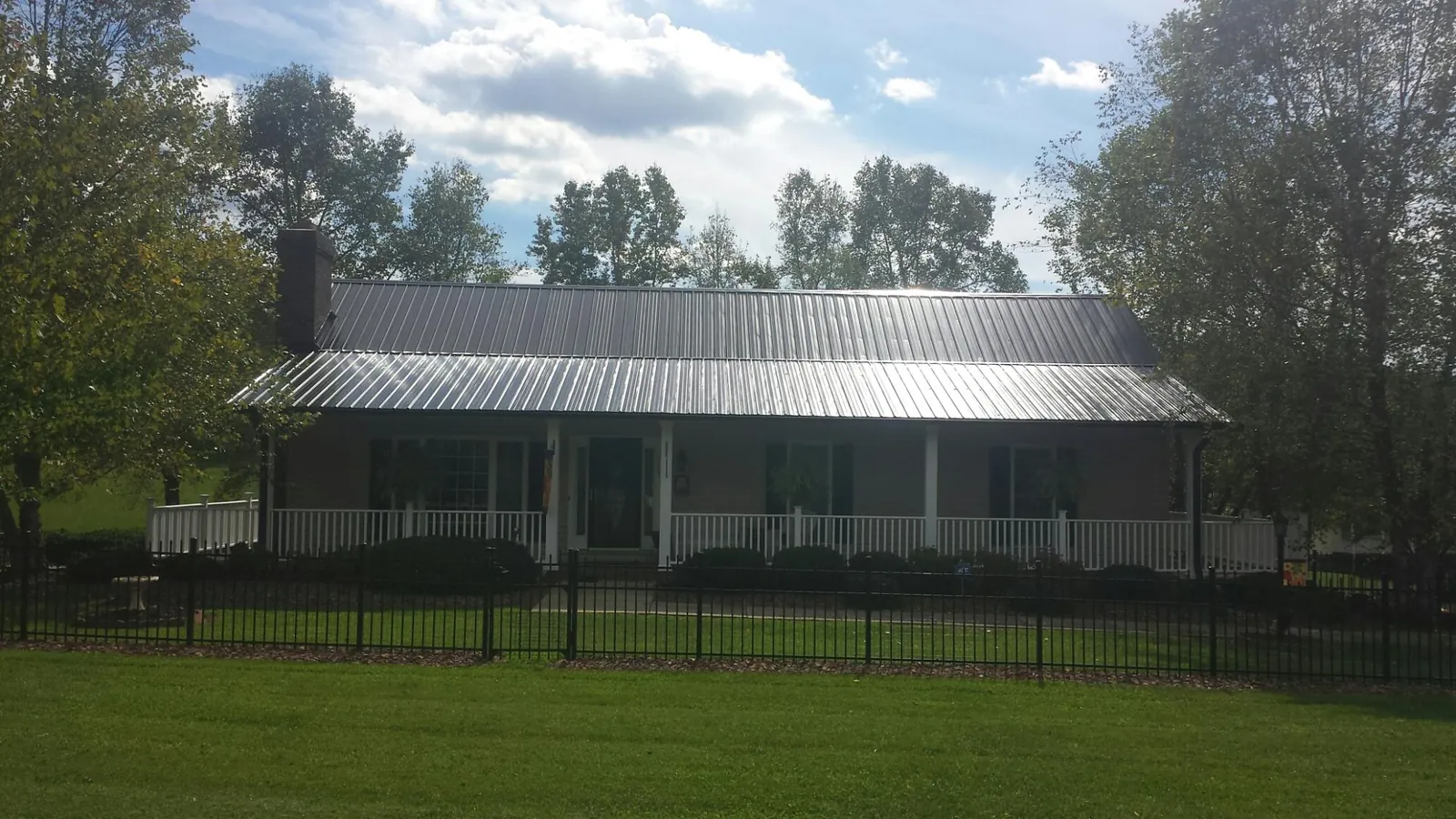 Gray metal roof on a brick ranch with a full width front porch — Gutter Guard Installation work by our crew in Columbus
